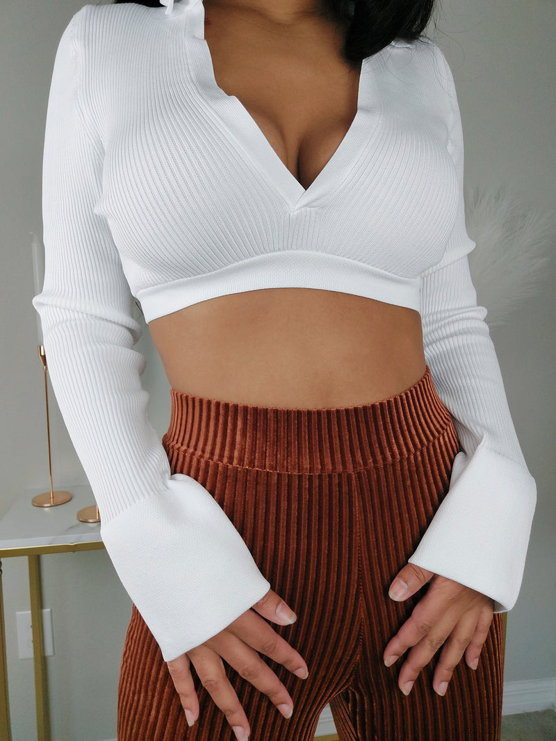 Crisp white long-sleeved crop top with a plunging V-neck. Chic white V-neck cropped blouse with long cuffed sleeves"