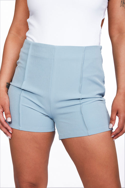 Light blue high waist dress shorts with elegant pintuck detailing, side zipper, and structured fit. Perfect for summer occasions and versatile styling